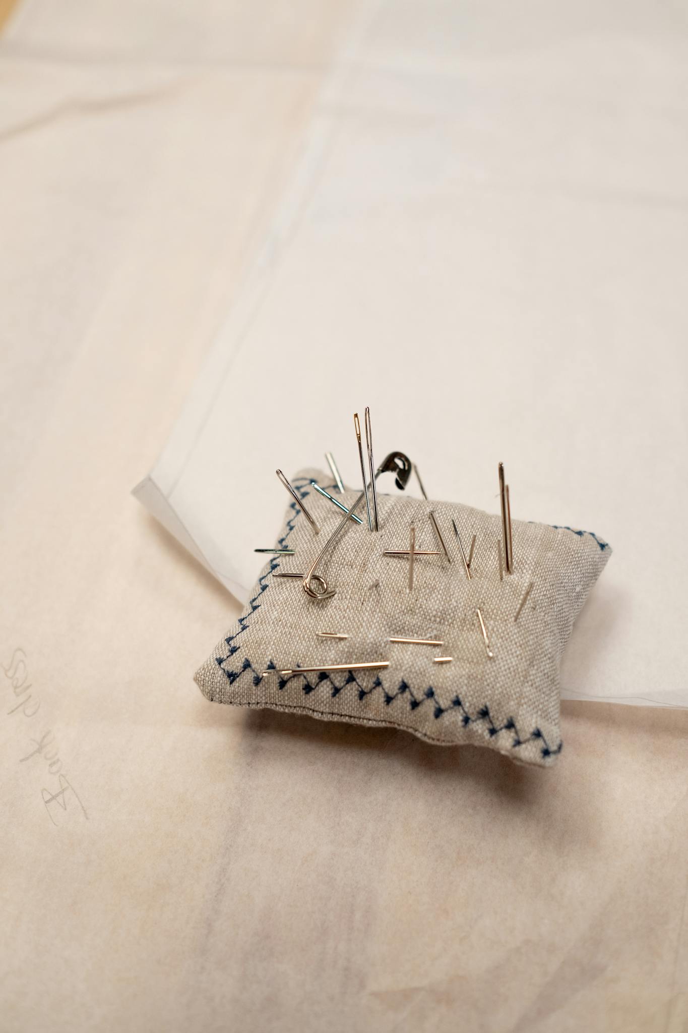 A needle cushion with various pins and needles in a sewing workshop setting.
