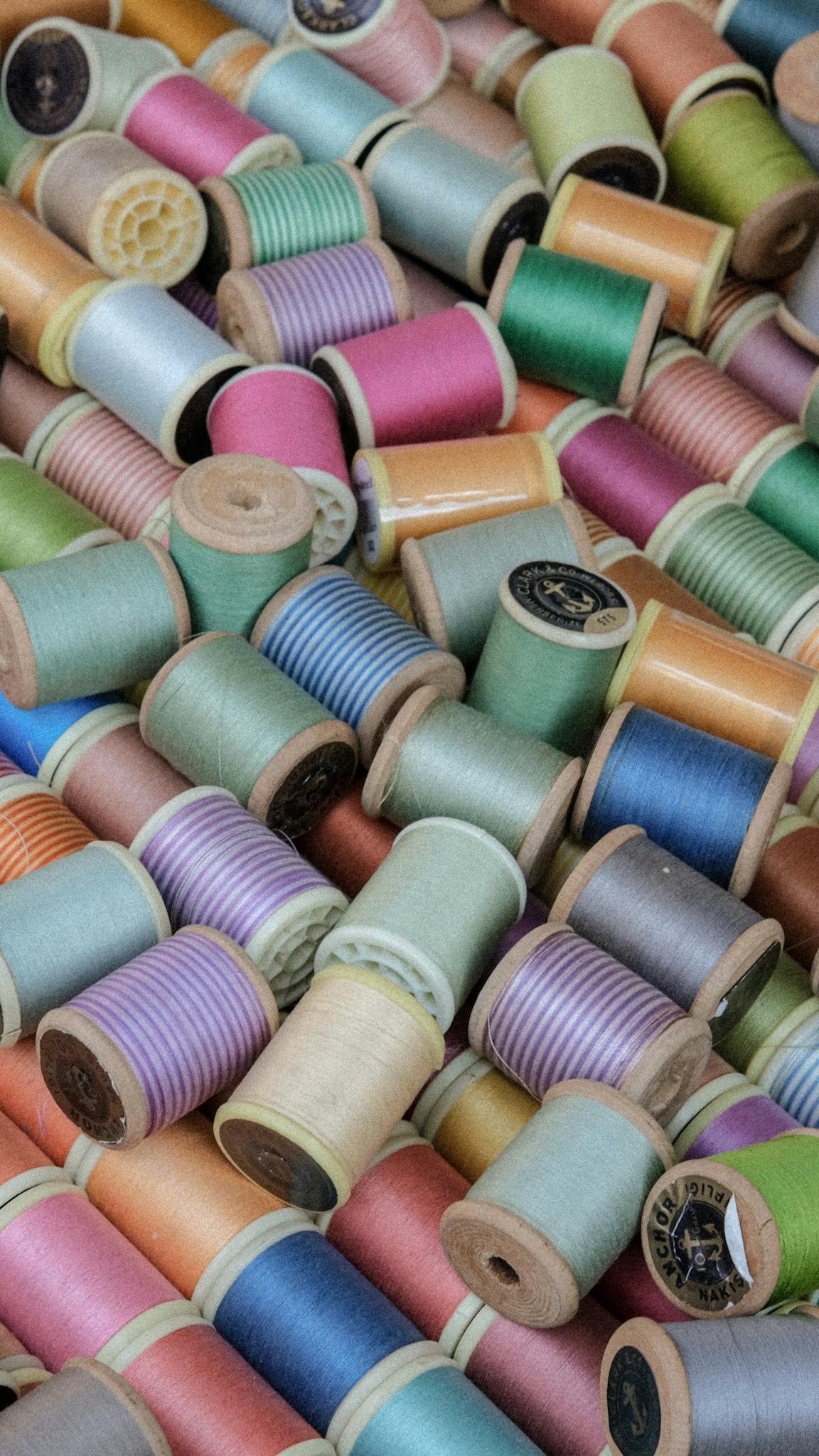 Vibrant close-up of various colored sewing thread spools for crafting and textile projects.